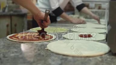 一组厨师把番茄酱均匀地放在披萨面团圈上